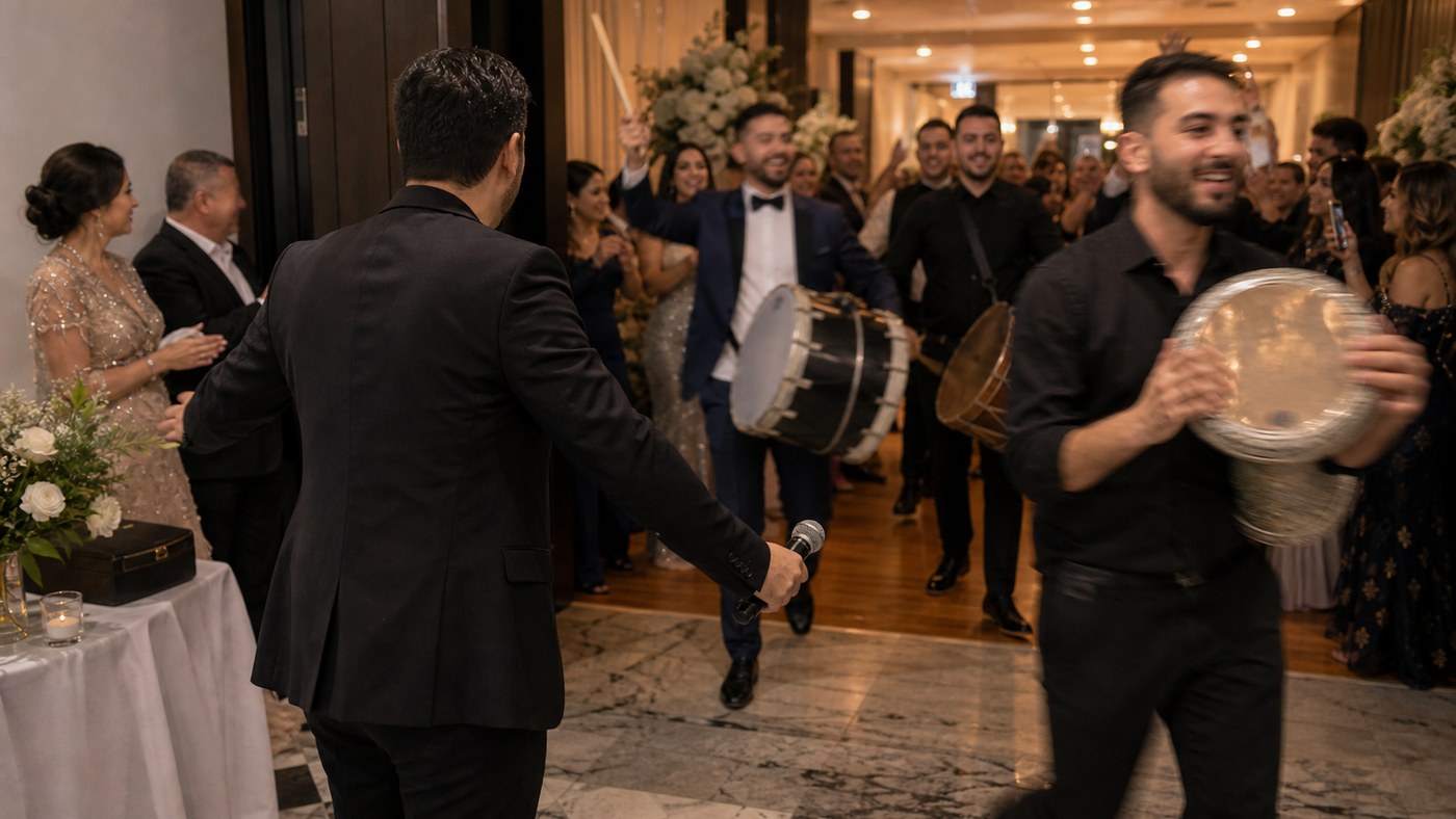 Candid Lebanese wedding zaffe entrance with guests clapping around the couple in warm reception light